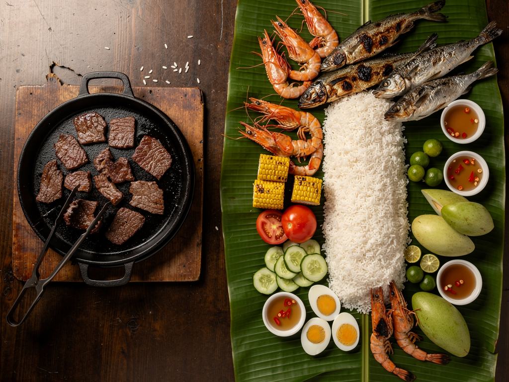 Korean Food vs Filipino Food (2026): The Honest UAE Guide 3 a Filipino boodle-fight spread on banana leaves beside a Korean beef grill
