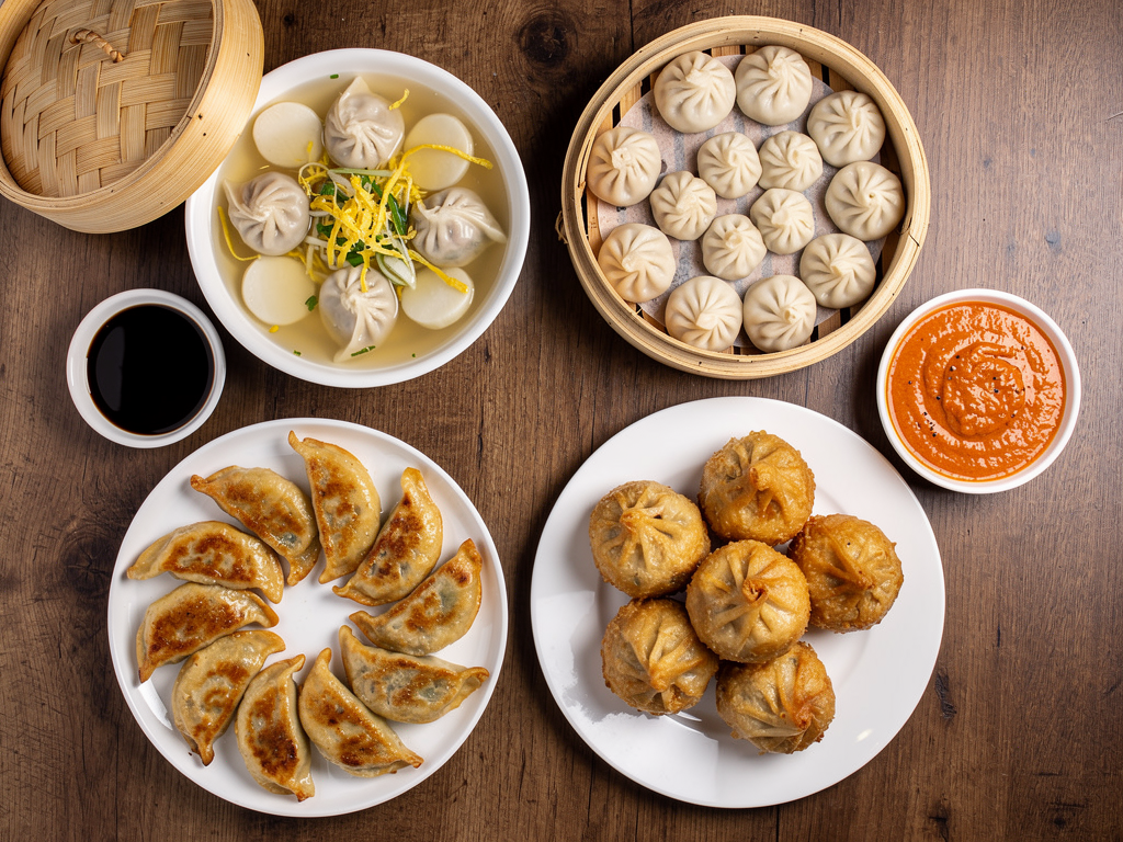 Mandu vs Momos (2026): The Honest UAE Guide 3 overhead spread of Korean pan-fried and steamed mandu with dumpling soup beside steamed and fried momos with chutney